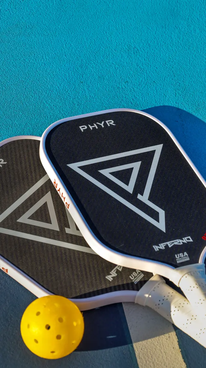 Two Inferno paddles and a ball at the baseline